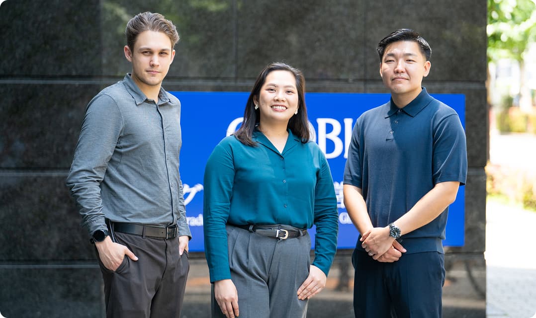 Three GLOBIS students standing together outside in front of the GLOBIS sign.