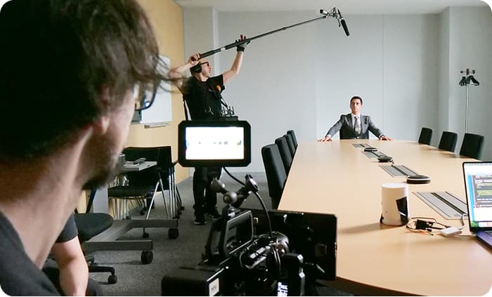 Behind-the-scenes video production crew filming an instructor at a conference table for an e-learning video.