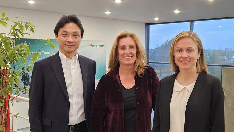 The members of Terumo Corporation standing together in an office setting in front of a company sign.